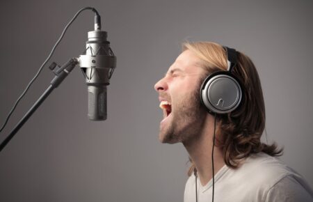 בחור עם אוזניות שר מול מיקרופון באולפן